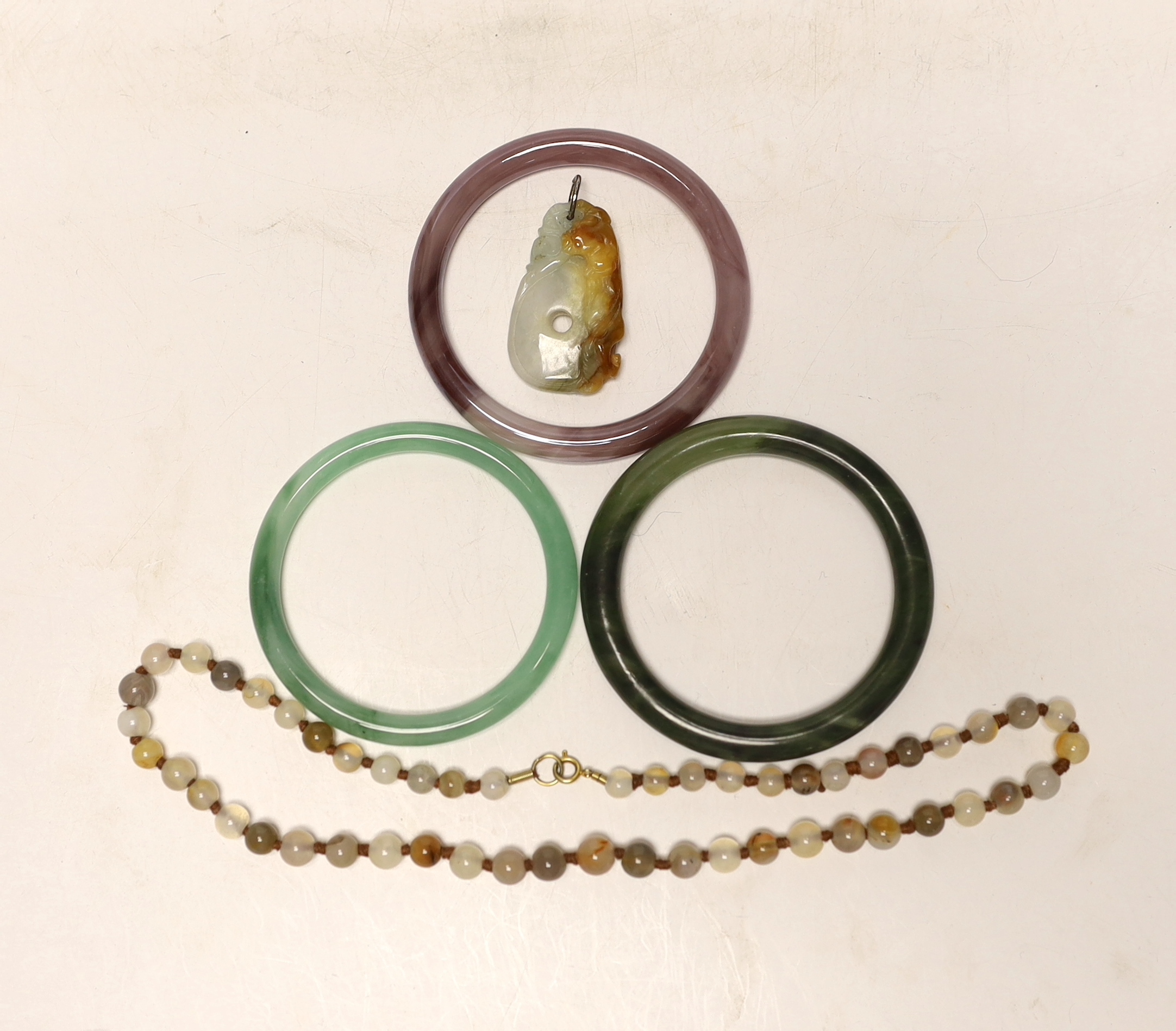 Two Chinese jade bangles, another, a jade pendant and beads